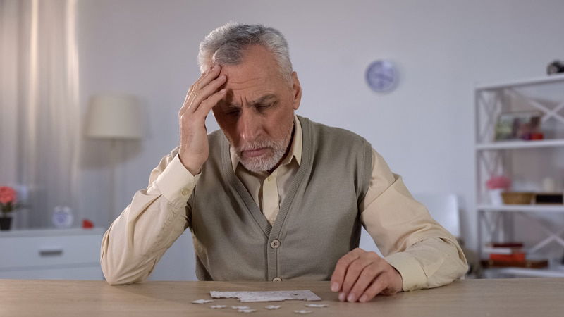 oudere man aan het nadenken bij een puzzel