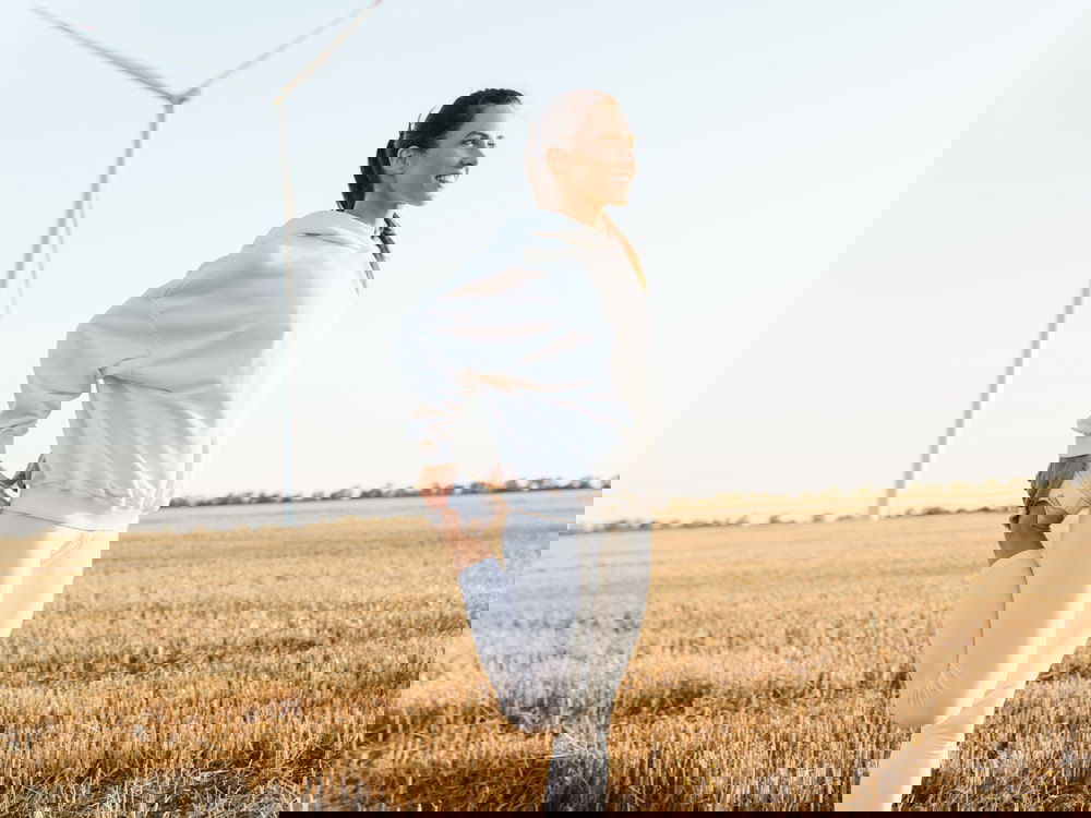 Woman in white sport in field with windmill in background ready to detox