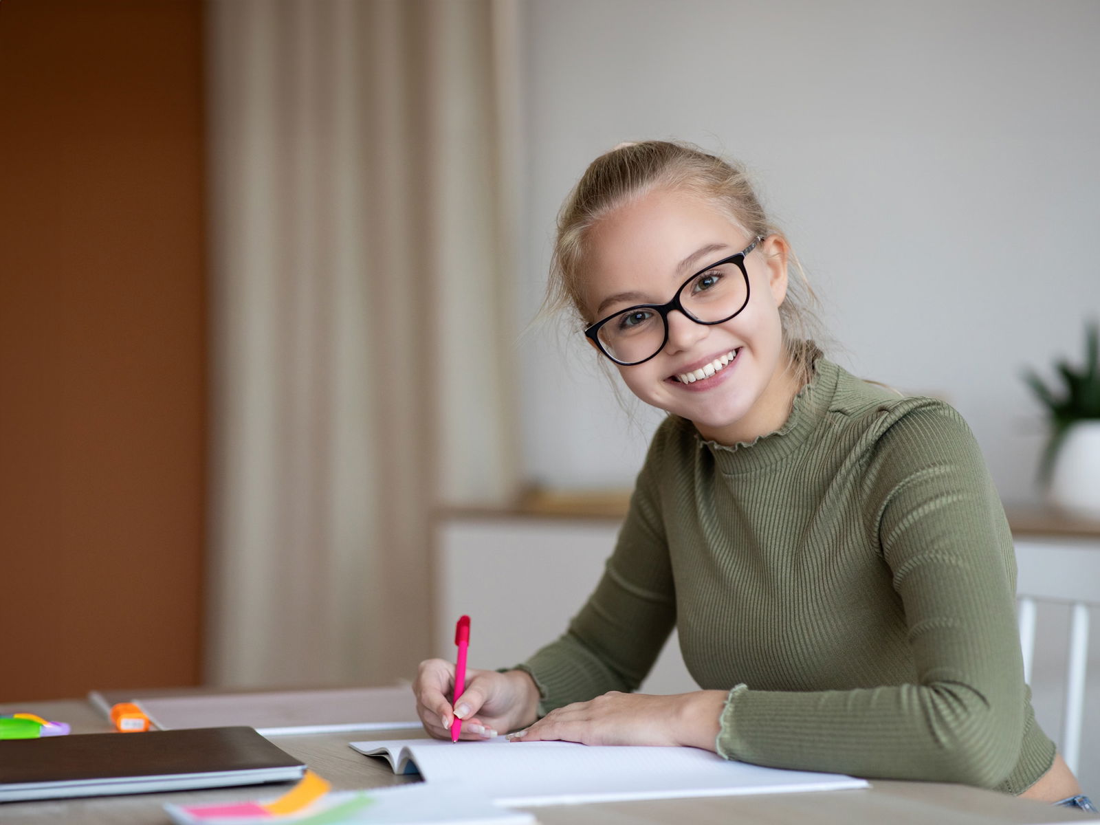 mooi schoolmeisje schrijft in notitieblok en lacht